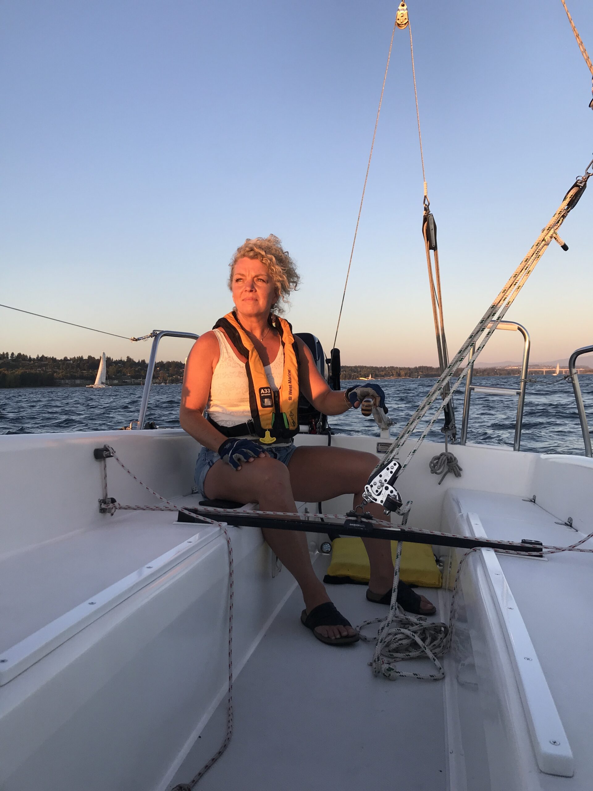 woman in life jacket sitting on sailboat